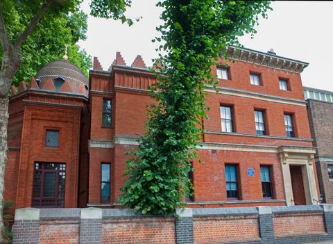 Architecture. Two of three sections making up a red brick building have stepped, triangular crenelations across the rooflines. A dome rises on the leftmost section. The section at the other end is the llargest. It is flat-faced and has an intricately carved cornice.