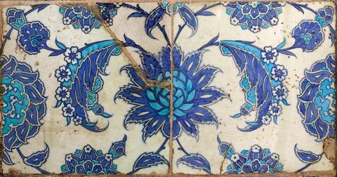 Tiles. A design of pale and intense blue flowers are painted across two tiles.