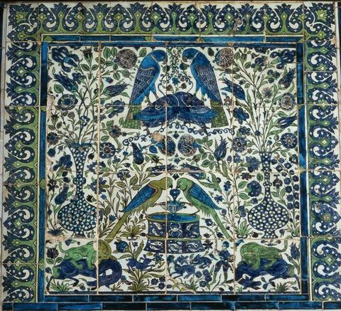 Tiles. Sixteen tiles in a grid of four by four are painted with a vertically, mostly symmetrical design of birds, animals, flowers, vases, and one person in tones of intense blue and green against a white background.